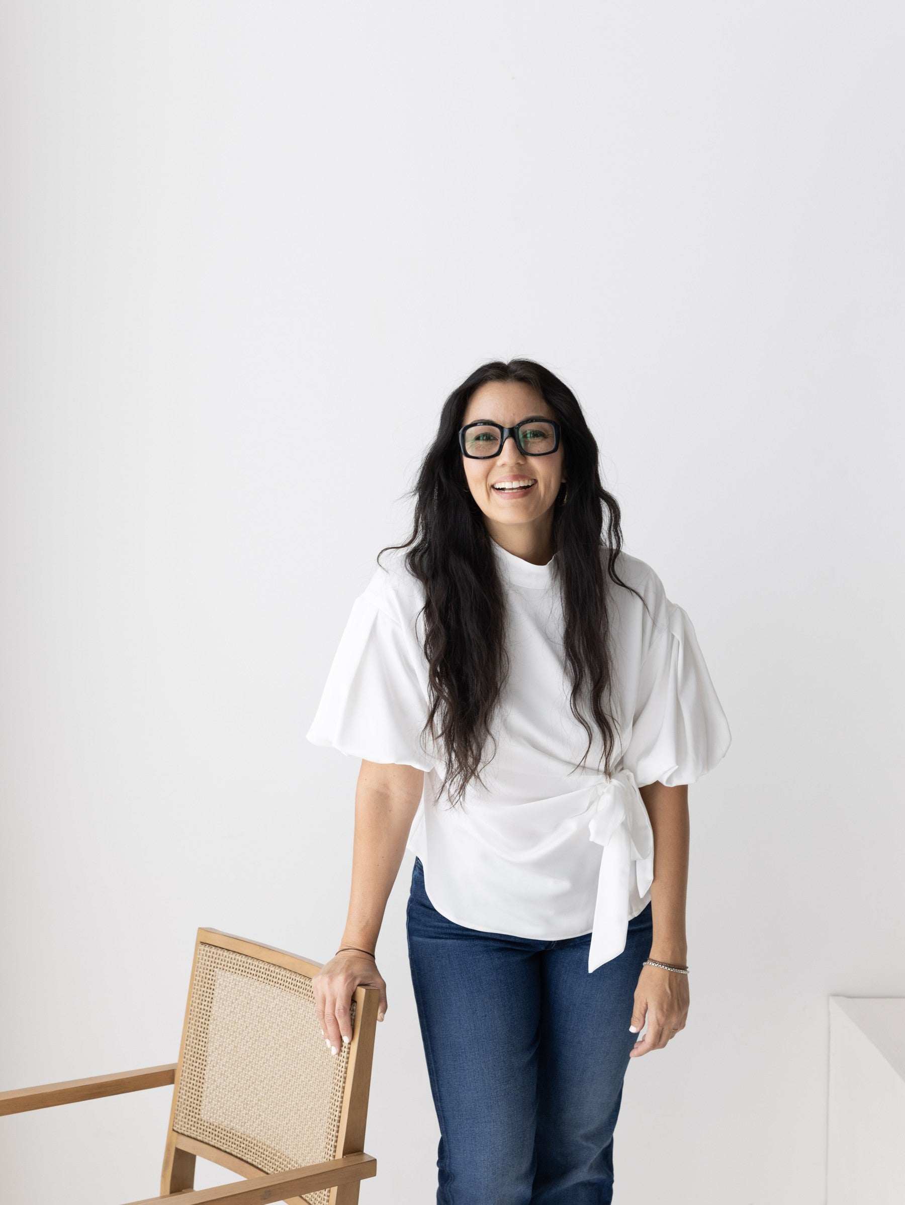 Smiling woman in a white wrap top and dark denim