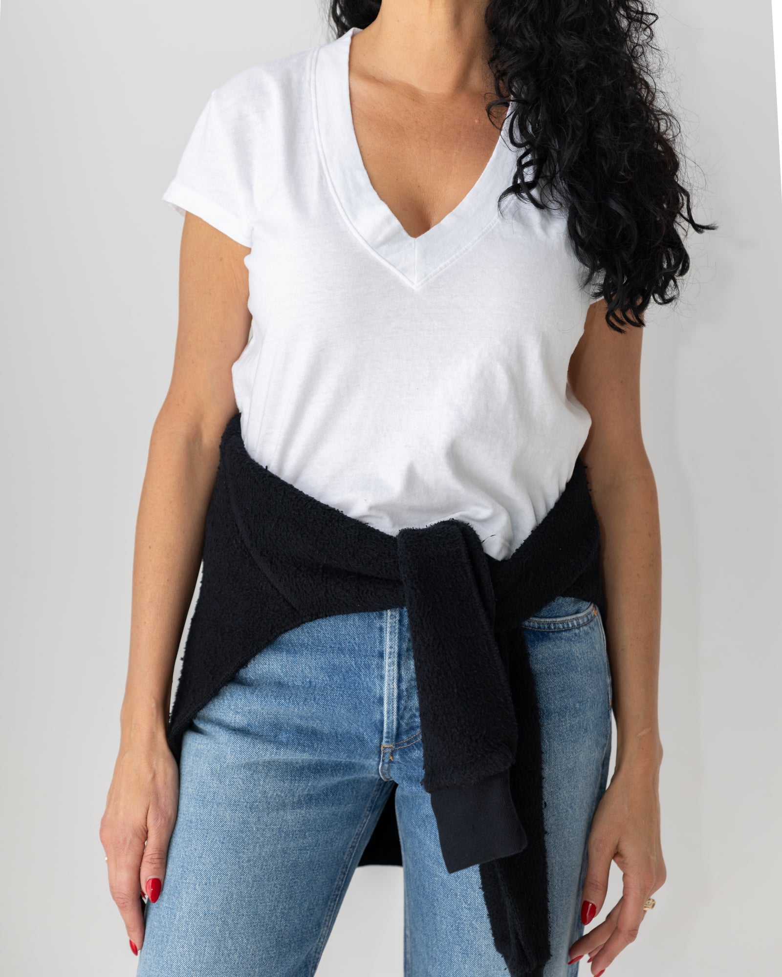 Two women wearing easy layers and denim by the wood slat wall